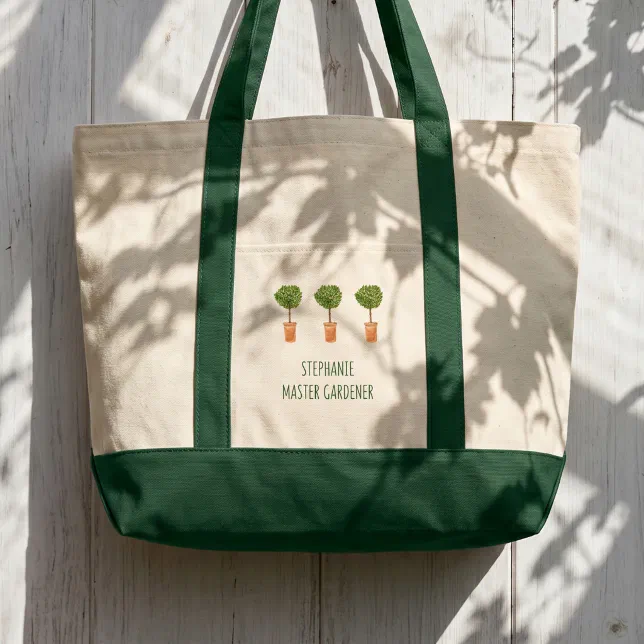 A dark green and cream tote bag with plant motif displayed on a white wooden background.