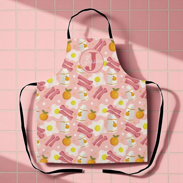 Personalized Retro Breakfast Pattern Apron (Whimsical pink apron with fried eggs, bacon, milk, and oranges for sunny breakfast vibes.)