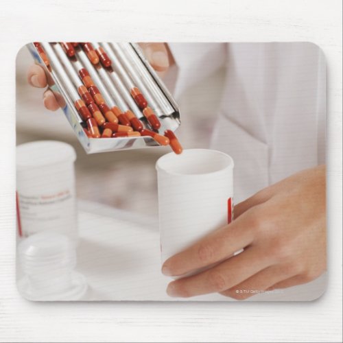 Pharmacist in drug store measuring pills into mouse pad