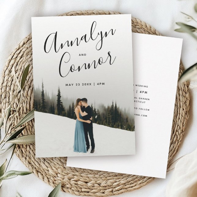 Photo Modern Script | Simple Clean Wedding Invitation (Wedding invitation with a couple embracing on snowy ground, framed by tall evergreens. )