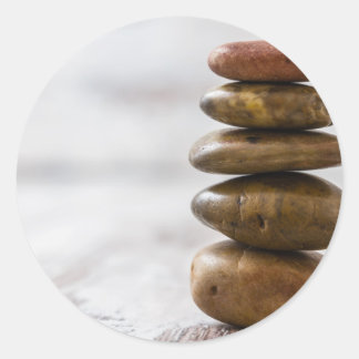 Pile of dark colored stones on white background classic round sticker