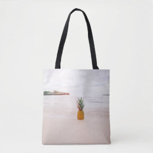 Pineapple on sand near beach tote bag