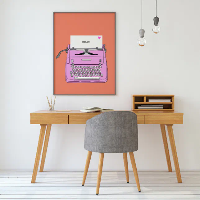A pink and orange retro typewriter poster is hanging on a white wall with a desk and a chair situated in front.