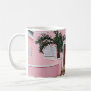 Pink and white concrete house near green trees und coffee mug