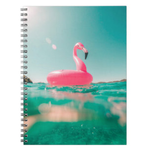 Pink flamingo swim ring on body of water in summer notebook