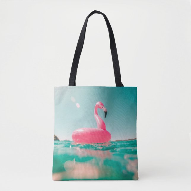 Pink flamingo swim ring on body of water in summer tote bag (Front)
