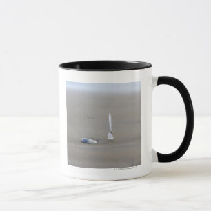 plastic fork sticking in sandy beach beside mug