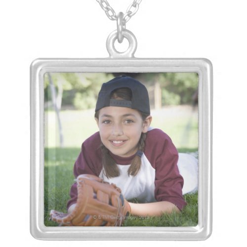 Portrait of girl lying on ground with baseball silver plated necklace