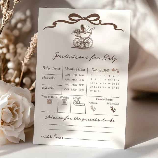 A 'baby prediction' card propped up on a table with dried flowers and warm beige roses placed artfully around it!