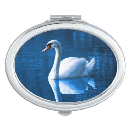 Pretty white swan floating on a blue lake mirror for makeup