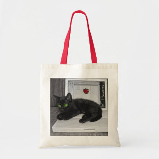 Prunella black cat lounging on laptop tote bag
