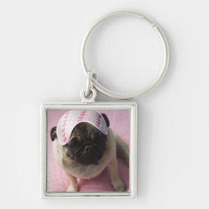 Pug dog with eye mask on head sitting on bed, keychain