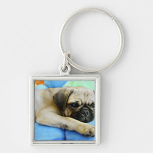 Pug laying on pillows keychain