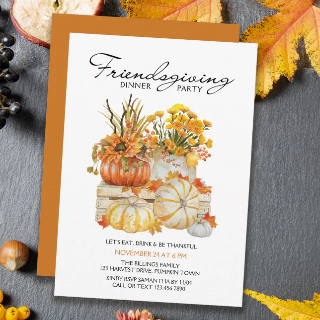 A Friendsgiving-themed invitation set against a grey countertop with various autumnal foliage scattered around it.