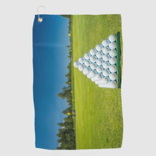 Pyramid of golf balls on a green field Golf Towels