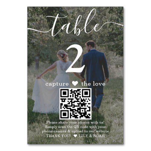 QR Code 2 Photo Capture the Love Wedding White Table Number - Add a personalized finishing touch to wedding reception decorations with custom photo & QR Code table number cards. Pictures and all text are simple to customize, and can be different or the same on front and back. If preferred, change "capture the love" to "honeymoon fund," "a special thanks," "menu," "our love story" or other text of your choice. (IMAGE PLACEMENT TIP: An easy way to center a photo exactly how you want is to crop it before uploading to the Zazzle website.) By scanning the QR code with their phone camera, guests are sent directly to a wedding website or other online location with any important / entertaining information, such as a video message, digital payment app, or social media page. The two-sided black and white design features modern minimalist typography, handwritten script calligraphy, 2 custom QR codes, and your pictures. These elegant and unique table number cards make a stylish addition to a special day celebration. Example photo on front is by Tim Stagge on Unsplash.
