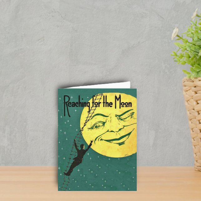 Reaching for the Moon Note Card (Man climbing ladder to reach yellow winking moon with face on emerald green with stars notecard.)
