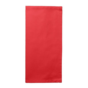 Red and orange crayons lying side by side on a whi cloth napkin
