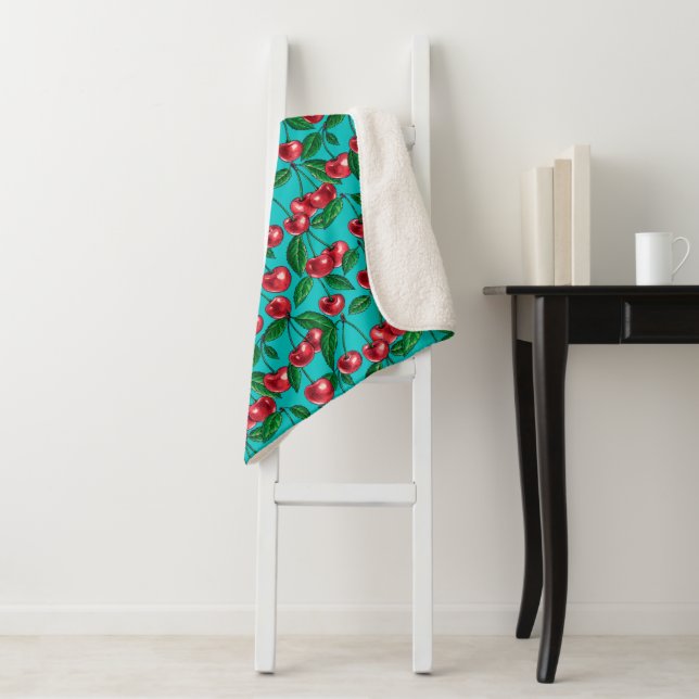 Red cherries on turquoise sherpa blanket (In Situ)