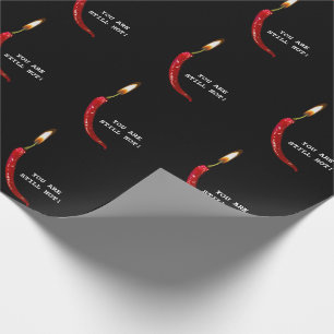 Red pepper with candle flame on black wrapping paper