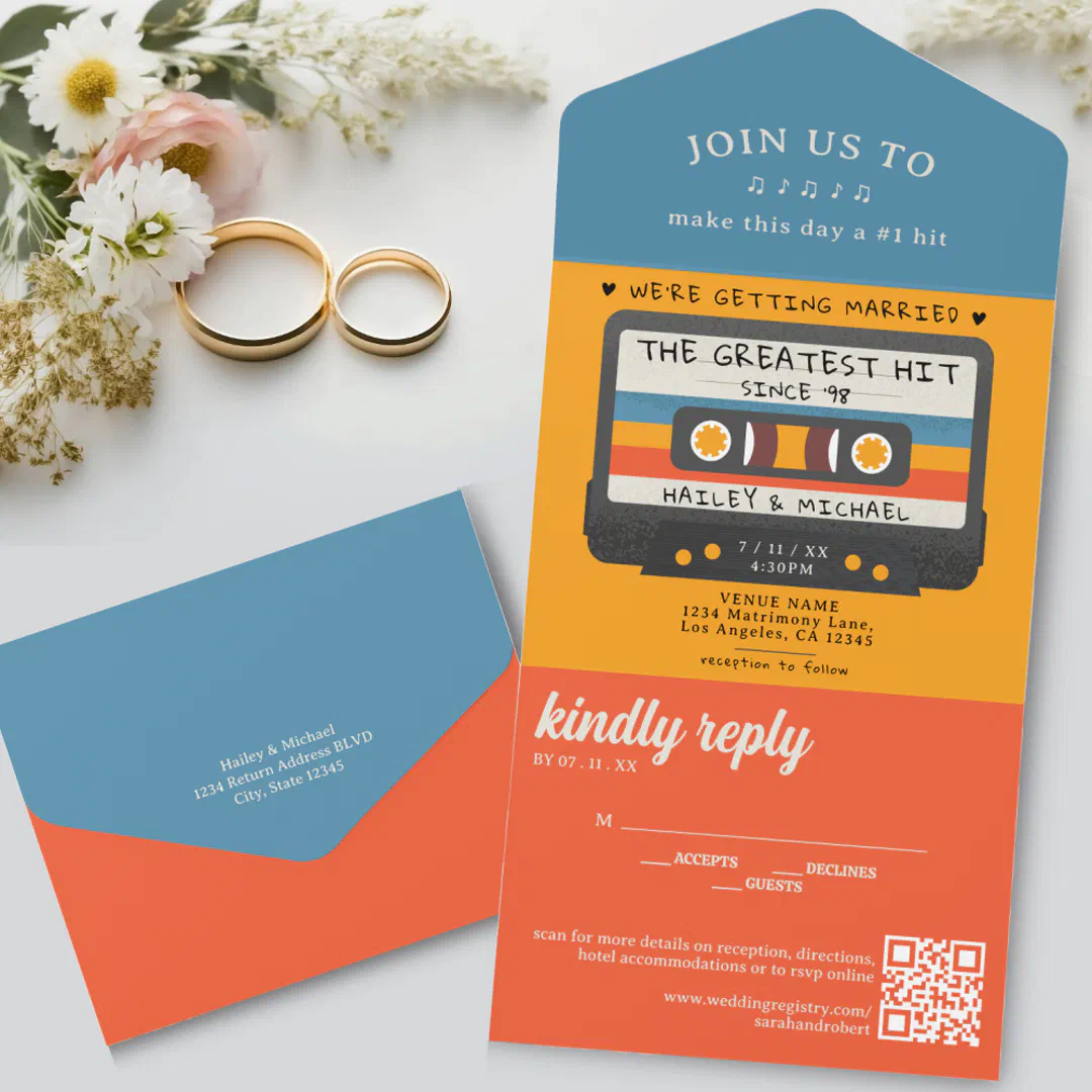 An all-in-one retro wedding invitation featuring an illustrated cassette tape design with a built-in reply section, displayed with a blue envelope, gold wedding bands, and white daisies.