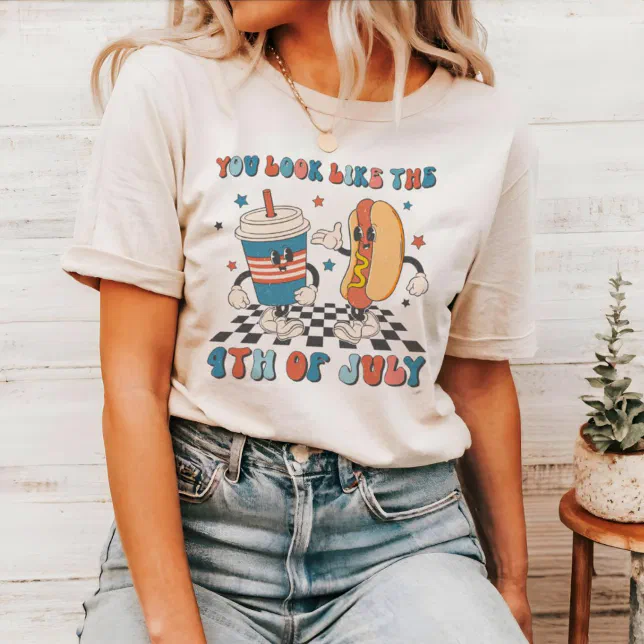 A woman wearing jeans and a funny t-shirt with a hot dog and soda design.