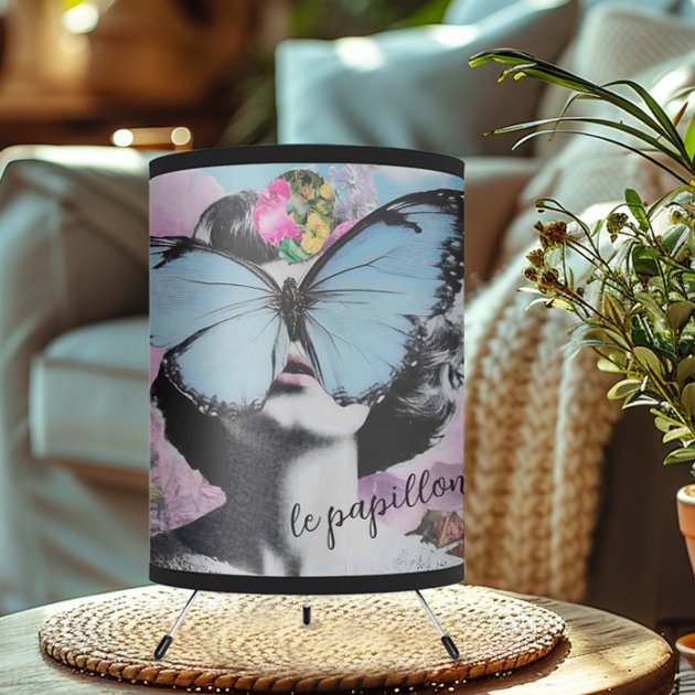 A lamp featuring a collage with a woman with a butterfly covering her eyes, flowers in pink and blue pastel colors a the writting papillon on it.