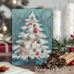 Retro Vintage 1950s White Christmas Tree Custom Holiday Card<br><div class="desc">Retro Vintage 1950s White Christmas Tree Custom Holiday Card. This beautiful mid-century illustration features a white Christmas tree adorned with colorful ornaments and candy canes. The blue background is highlighted with a gently falling snow and a green ribbon of musical notes is lofting through the air. Personalize by customizing the...</div>