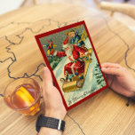 Retro Vintage Merry Christmas Santa Boy Sledding  Holiday Card<br><div class="desc">This Vintage Themed Retro Christmas Winter Brown Title and Red Frame Background, painting Santa sledding with a baby Boy and gifts near christmas pine tree with toys Holiday Postcard with Chrismas greeting "A Merry Christmas" and Backside place for your wishes which you can customize will be perfect for your holiday...</div>