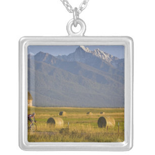 Road bicyclists race down back country road in silver plated necklace