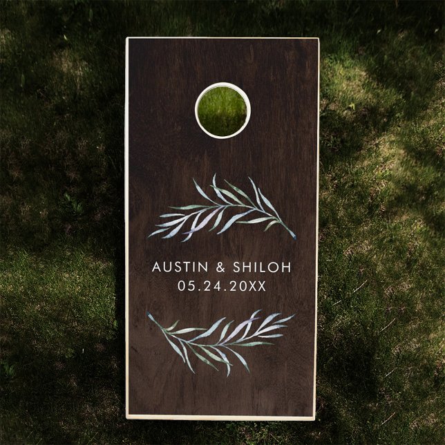Romantic Botanical Greenery Modern Elegant Wedding Cornhole Set (Cornhole board on grass features a dark wood design with white laurel leaves. name and date below)