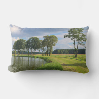 Rural landscape with trees, water and cloudy sky lumbar pillow