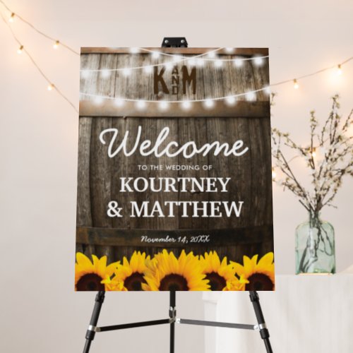 Rustic Sunflower Wedding Welcome Foam Board - Sunflower vineyard wedding welcome foam board sign featuring a rustic country barn dark oak barrel background, twinkle string lights, golden yellow sunflowers, your initials, and modern wedding welcome template that is easy to personalize.
