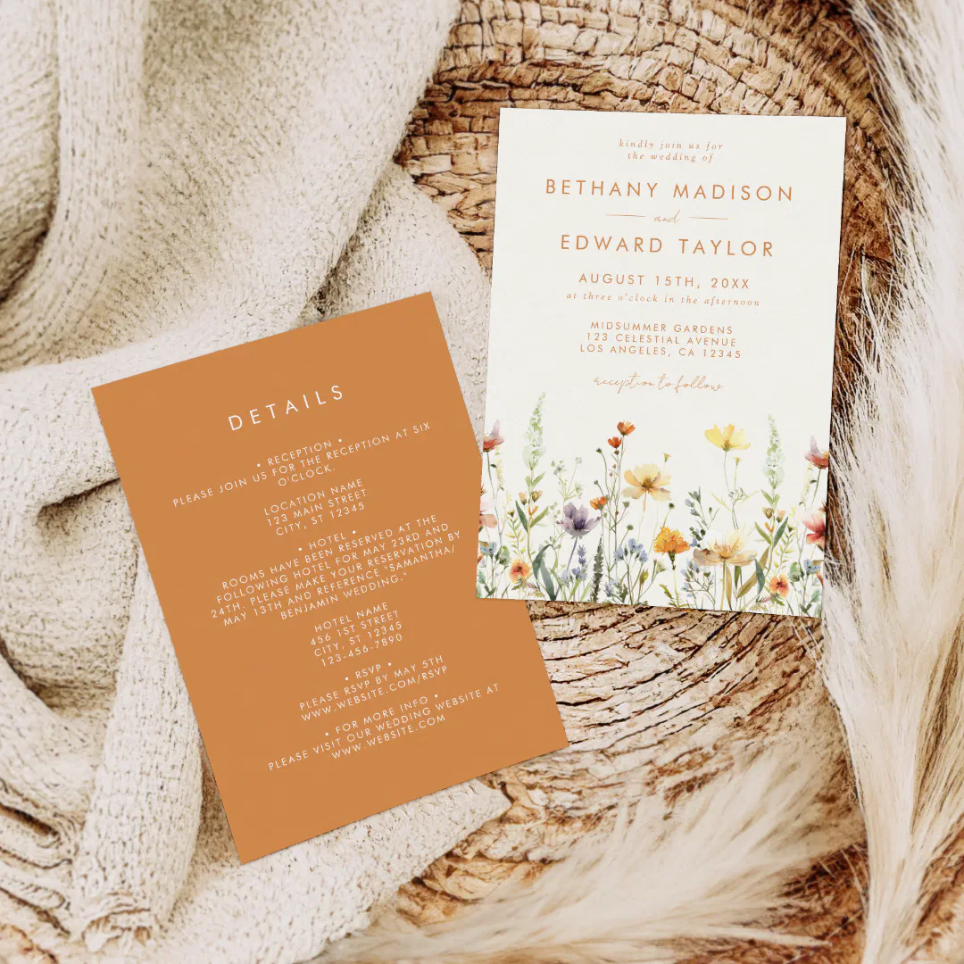 A blanket, a straw hat, and feathers create a beige neutral background. The invitation is in the center unveiling shades of orange and wild flowers.