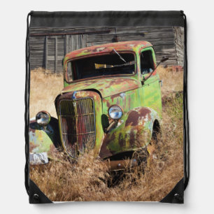 Rusting car in front of abandoned farm drawstring bag