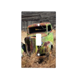 Rusting car in front of abandoned farm light switch cover