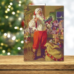 Santa and Toys Vintage Christmas Card<br><div class="desc">This holiday greeting card features a wonderful vintage fine art image of Santa Claus examining a toy locomotive in his shop, with various other toys on the shelves and workbench around him. His toy sack complete with jingle bells sits on the floor in front of him. The inside text is...</div>