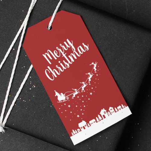 Santa Claus w sleigh  reindeers above the houses Gift Tags
