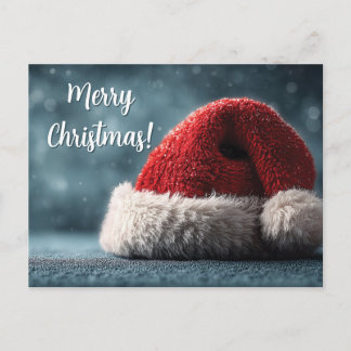 Santa Hat Resting on Snowy Surface with Greeting Postcard