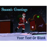 Santa On The Roof - Season's Greetings Cutout<br><div class="desc">Santa Claus is seen on the roof of a house after delivering presents. His sleigh's red and green navigation lights are reflected on the rooftop snow,  and Santa's personal North Pole license plate is visible.Text reading "Season's Greetings" also appears along with a place for your own text.</div>