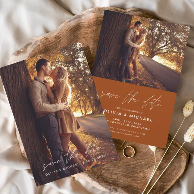 A terracotta-colored Save the Date. Both sides of the Save the Date can be seen, and both are lying on a wooden stand. A woman is shown kissing her fiancé.