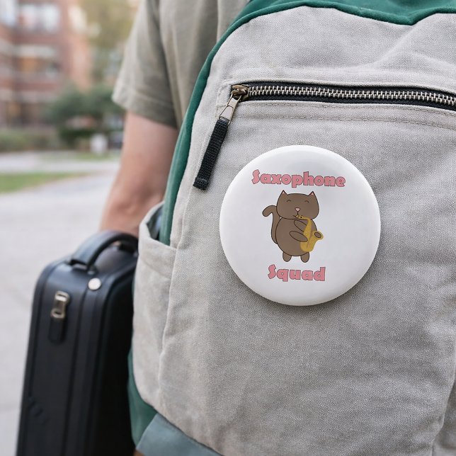 Saxophone Squad Cute Kawaii Cat Pink Button (A pin featuring a brown cat playing saxophone and the words saxophone squad in pink.)