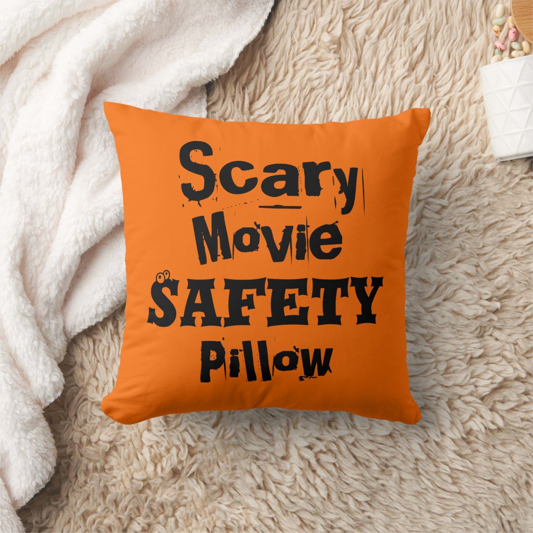 Orange throw pillow with black text styled on a fluffy blanket.