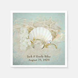 seashells and wedding rings in sand napkins