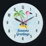 Seasons Greetings Pink Flamingo in Santa Hat Large Clock<br><div class="desc">Clock with the text: Seasons Greetings. A whimsical drawing of a pink flamingo wearing a red santa hat. Standing on a mound of yellow beach sand with a green and brown coconut palm tree in the back. Light blue background with a faint polygonal pattern. Cute and fun festive tropical design....</div>