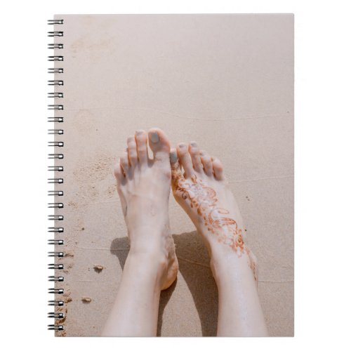 Selective focus photography of feet with tattoo on notebook