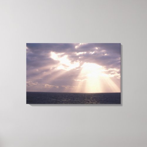 Setting sun shining through clouds over ocean canvas print