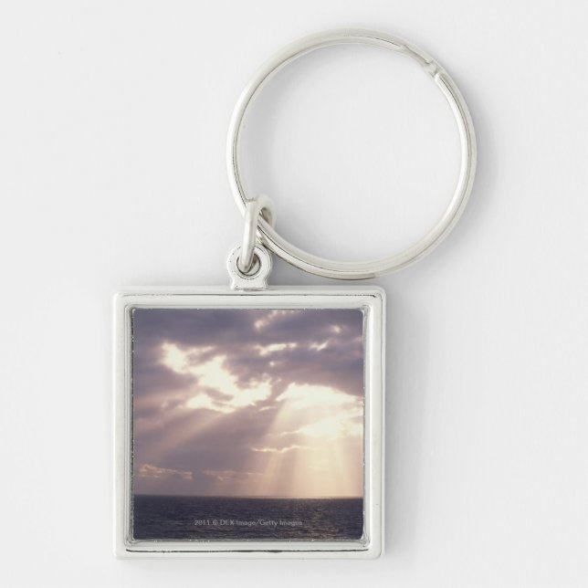 Setting sun shining through clouds over ocean keychain (Front)