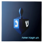 Shiny Blue Dreidel Tile<br><div class="desc">A modernistic,  metallic blue dreidel against a dark,  night-like background.  Two of the Hebrew letters found on a dreidel,  nun and shin,  glow brightly.  Hebrew text reading "Chag Chanukkah Sameach" (Happy Hanukkah) also appears in glowing blue and white.</div>