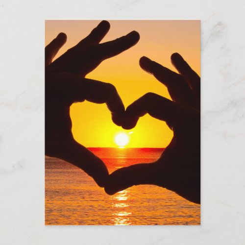 Silhouette hand in heart shape and sunrise over th postcard